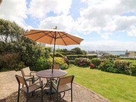 A garden with a table and chairs under an umbrella at Cwm Eilir in Criccieth