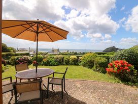 A garden with a table and chairs under an umbrella at Cwm Eilir in Criccieth