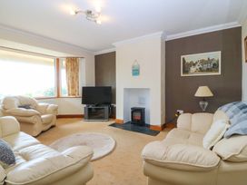 A living room with a sofa, television, and fireplace at Cwm Eilir in Criccieth
