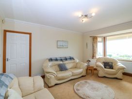 A living room with sofas and a door at Cwm Eilir Criccieth