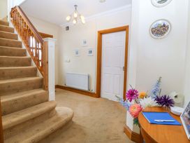 A hallway with a staircase and a door at Cwm Eilir in Criccieth