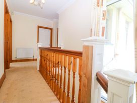A hallway with balustrade and door at Cwm Eilir in Criccieth