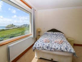 A bedroom with a bed and a window view at Cwm Eilir in Criccieth