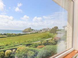 A view of the ocean and hill from a window at Cwm Eilir in Criccieth