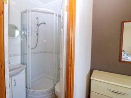 A bathroom with a shower, sink, and mirror at Cwm Eilir in Criccieth
