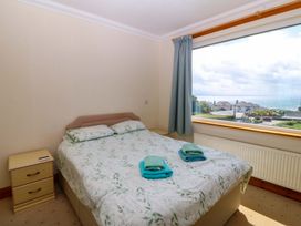 A bedroom with a bed and a view of the sea at Cwm Eilir in Criccieth