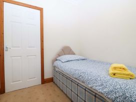 A bedroom with a single bed and a door at Cwm Eilir in Criccieth