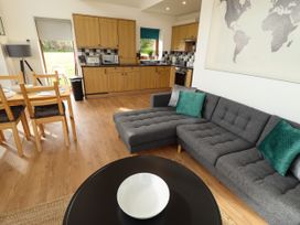 An open plan kitchen and living area with wooden cabinets gray sofa black round table and dining table at Lodge 3 in Thorpe-On-The-Hill