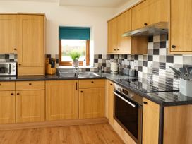 A kitchen with wooden cabinets black countertops and checkered tile backsplash at Lodge 3 in Thorpe-On-The-Hill