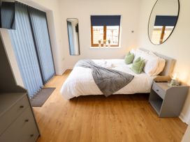 A bedroom with a double bed green pillows a gray throw a nightstand and a dresser at Lodge 3 in Thorpe-On-The-Hill