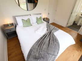 A bedroom with a double bed two side tables and a bathroom door at Lodge 3 in Thorpe-On-The-Hill