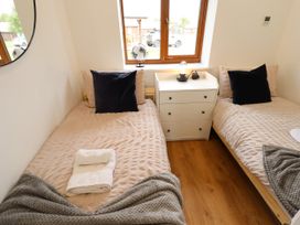 A bedroom with two single beds and a white chest of drawers with a lamp and globe on a windowsill at Lodge 3 in Thorpe-On-The-Hill