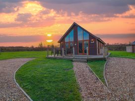 A cabin with a deck and chairs during sunset at Lodge 3 Thorpe-On-The-Hill