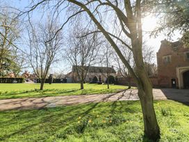 A garden with trees and house in the background at Lodge 3 in Thorpe-On-The-Hill