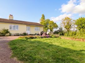 A house with deck chairs and flowers in the garden at Palace Bungalow St Weonards