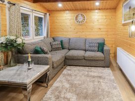 A wooden room with a gray corner sofa cushions and a clock above at Buttermilk Bridge in Dungiven