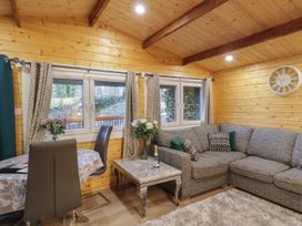 A living room with a gray sofa a coffee table with flowers and a bottle on it and a dining table with chairs at Buttermilk Bridge in Dungiven