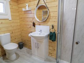 A bathroom with a toilet sink cabinet mirror towel rack and shower at Buttermilk Bridge in Dungiven