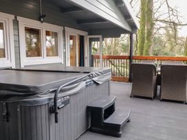 An outdoor covered deck area with a hot tub and a dining table with chairs at Buttermilk Bridge in Dungiven