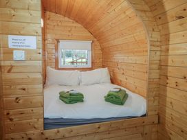A wooden cabin bedroom with a double bed two pillows two green towels and a small window at Pine in Dungiven Londonderry