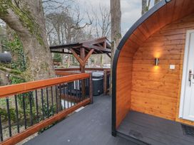 A wooden deck with railing surrounding a hot tub and the entrance to a wooden pod at Pine in Dungiven Londonderry