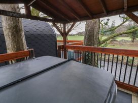 A covered wooden deck with a hot tub surrounded by trees and a view of a field at Pine in Dungiven Londonderry