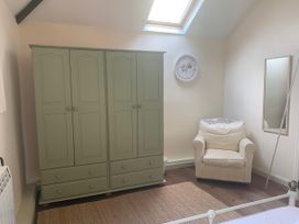 A bedroom with a wardrobe and an armchair at The Calf Pen in Colyton
