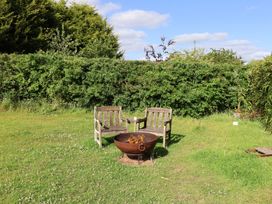 A garden with a fire pit and wooden chairs at The Hay Loft in Colyton