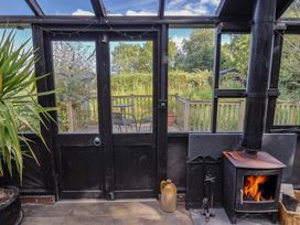 A conservatory with a wood stove and chairs in The Hay Loft in Colyton