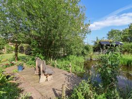 A garden with a wooden bench and a pond at The Hay Loft in Colyton