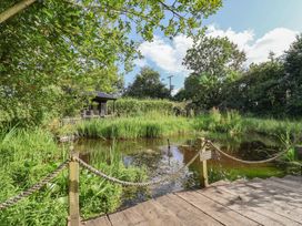 A garden with a pond and wooden deck at The Hay Loft in Colyton