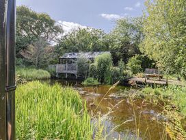 A garden with a pond and greenhouse at The Hay Loft in Colyton