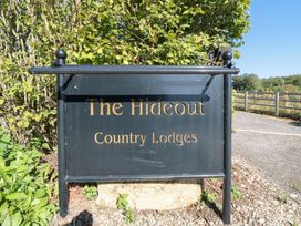 A sign for The Hideout Country Lodges with greenery at Stags Mount in Thornton Dale