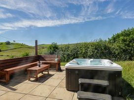 An outdoor area with a hot tub and wooden bench at Holly in Ulverston