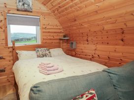 A bedroom with a bed and window in a wooden cabin at Willow in Ulverston