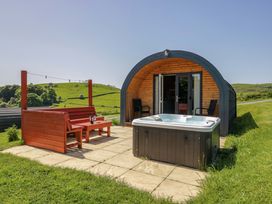 An outdoor seating area with a hot tub and wooden furniture at Willow in Ulverston