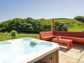 An outdoor area with a hot tub and a wooden seating area at Willow in Ulverston
