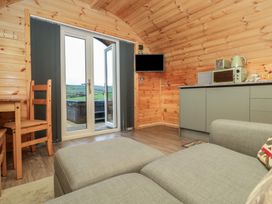 A living room with a sofa and kitchen area at Rowan in Ulverston