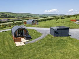 An outdoor area with two pods and a hot tub at Rowan in Ulverston