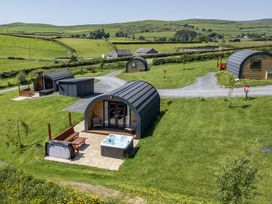 An outdoor area with log cabins and a hot tub at Rowan in Ulverston