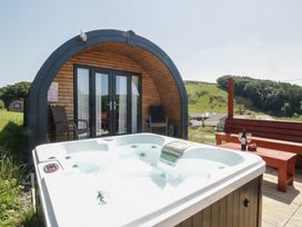 A hot tub in front of a wooden cabin at Rowan in Ulverston