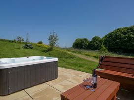 An outdoor area with a hot tub and wooden bench at Cherry in Ulverston