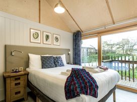 A bedroom with a bed and a window opening to a deck at Lodge 14 Corfe Castle