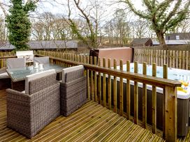 An outdoor area with a table and chairs next to a hot tub at Lodge 14 in Corfe Castle