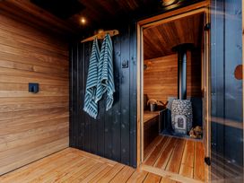 A sauna with a wood stove and towels hanging at Lodge 19 Corfe Castle