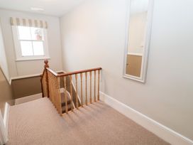 A hallway with a staircase and a mirror at Elkhorn in Southwold