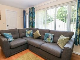A living room with a sofa and large windows at 14 The Dell Mundesley