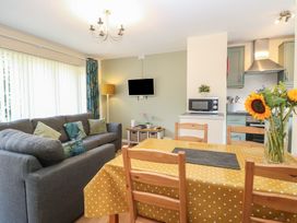 A living room with a sofa and dining table at 14 The Dell Mundesley
