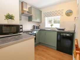 A kitchen with a microwave, oven, sink, and dishwasher at 14 The Dell Mundesley