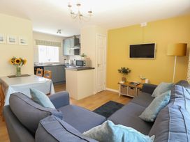 A living room with a sofa and dining area at 15 The Dell Mundesley